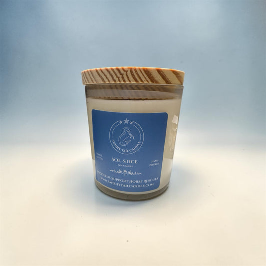 Swishy Tail Candle Sol-Stice soy wax candle in a glass jar with a rustic natural wood lid and blue label.
